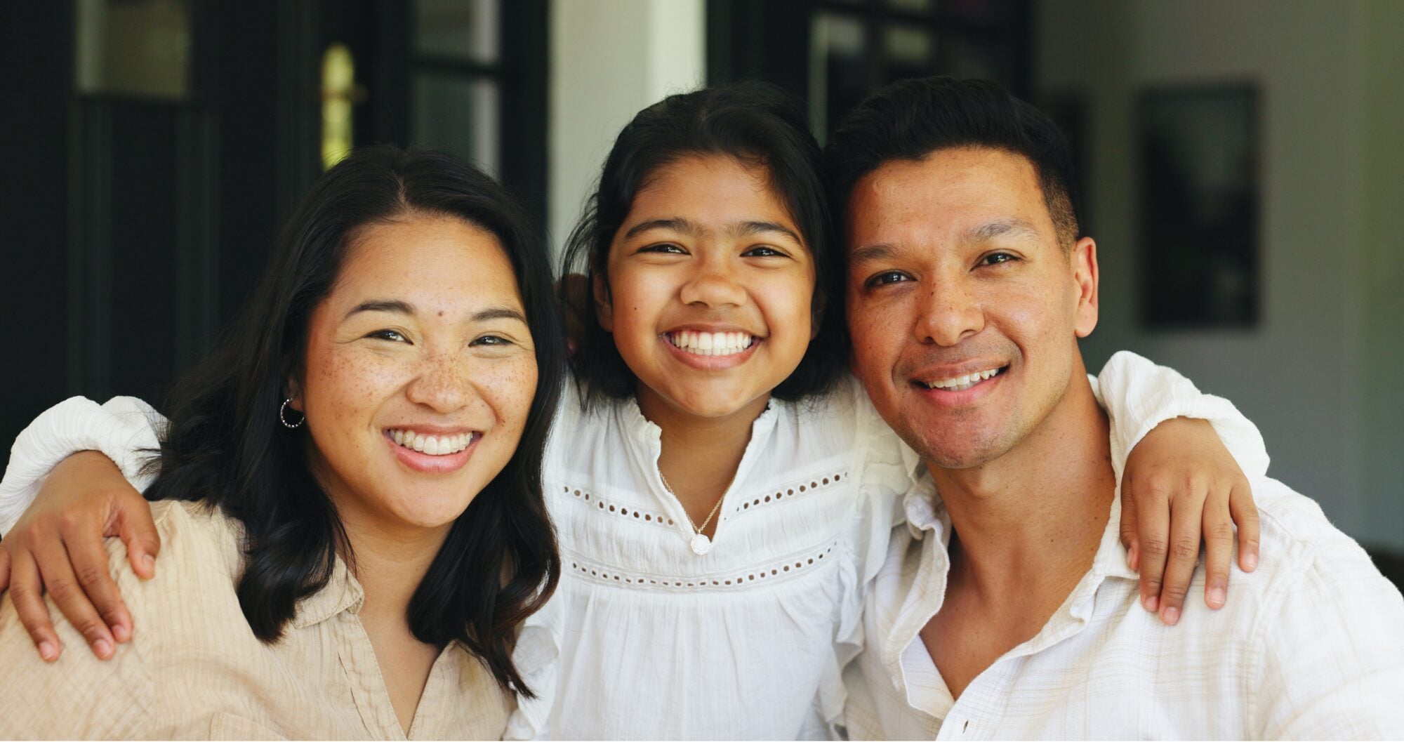 A mother, father and daughter smiling together