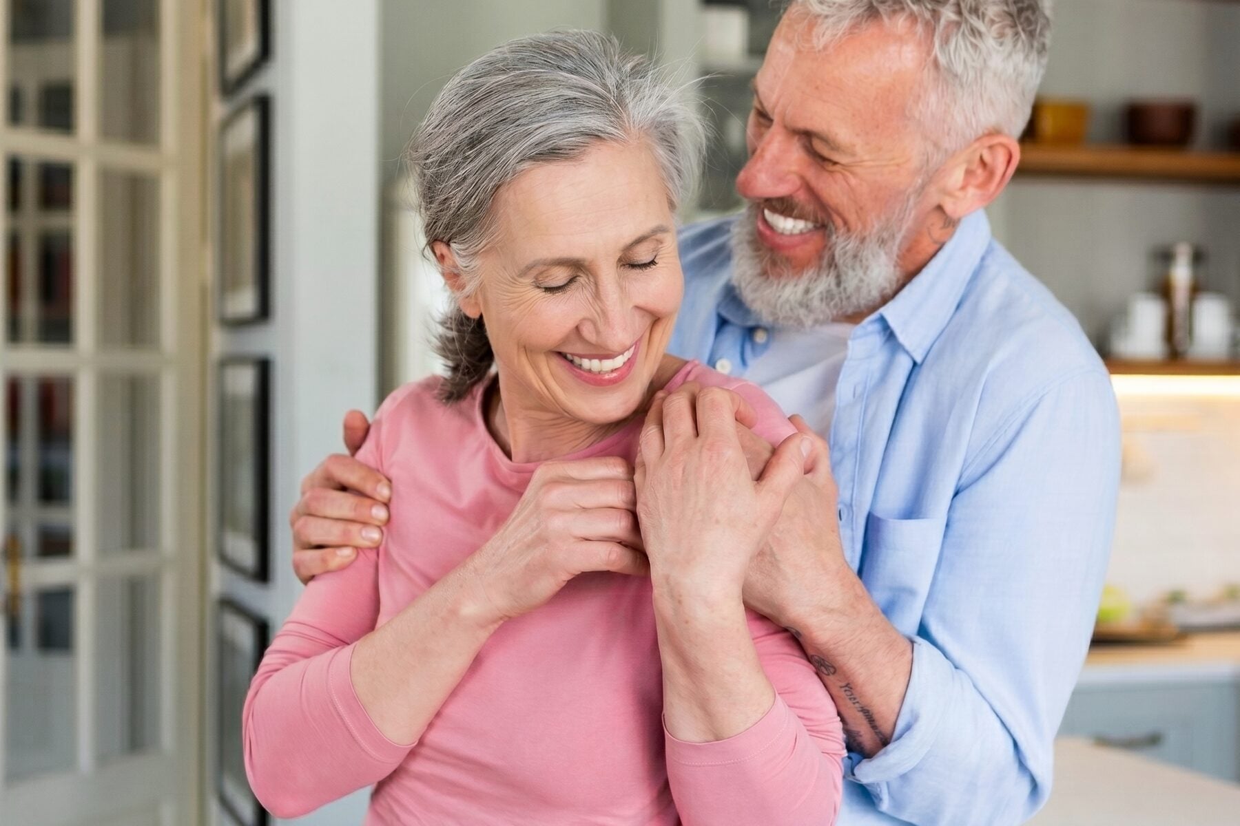 An older couple smiling together in their kitchen
